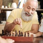 assisted living resident playing chess with grand children during a visit