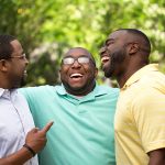 group of three african american men hugging and laughing