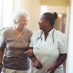 assisted living resident being accompanied by nurse down hallway