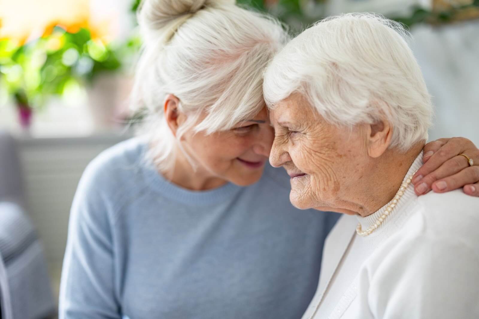 An elderly woman and her adult daughter sharing a heartfelt moment, symbolizing the compassionate care provided by senior living and memory care communities in Lincoln, NE.