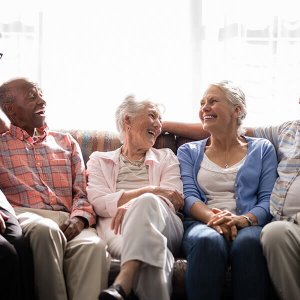 senior residents sitting on a couch together during a tour of an assisted living facility