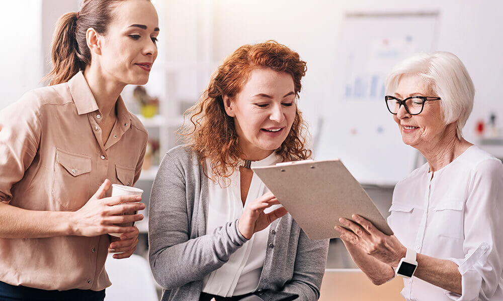 a group of multi-generational women work together in an office